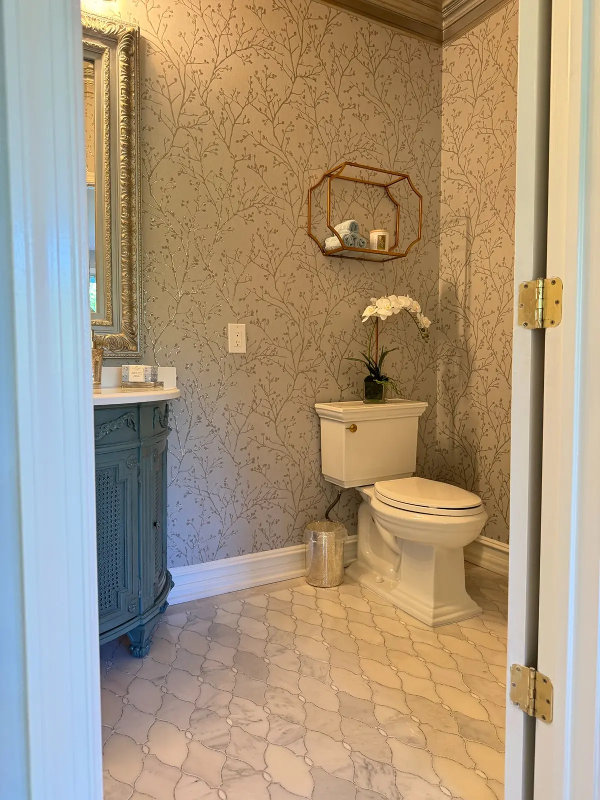Powder room with patterned wallpaper, a blue vanity and hexagonal tile flooring