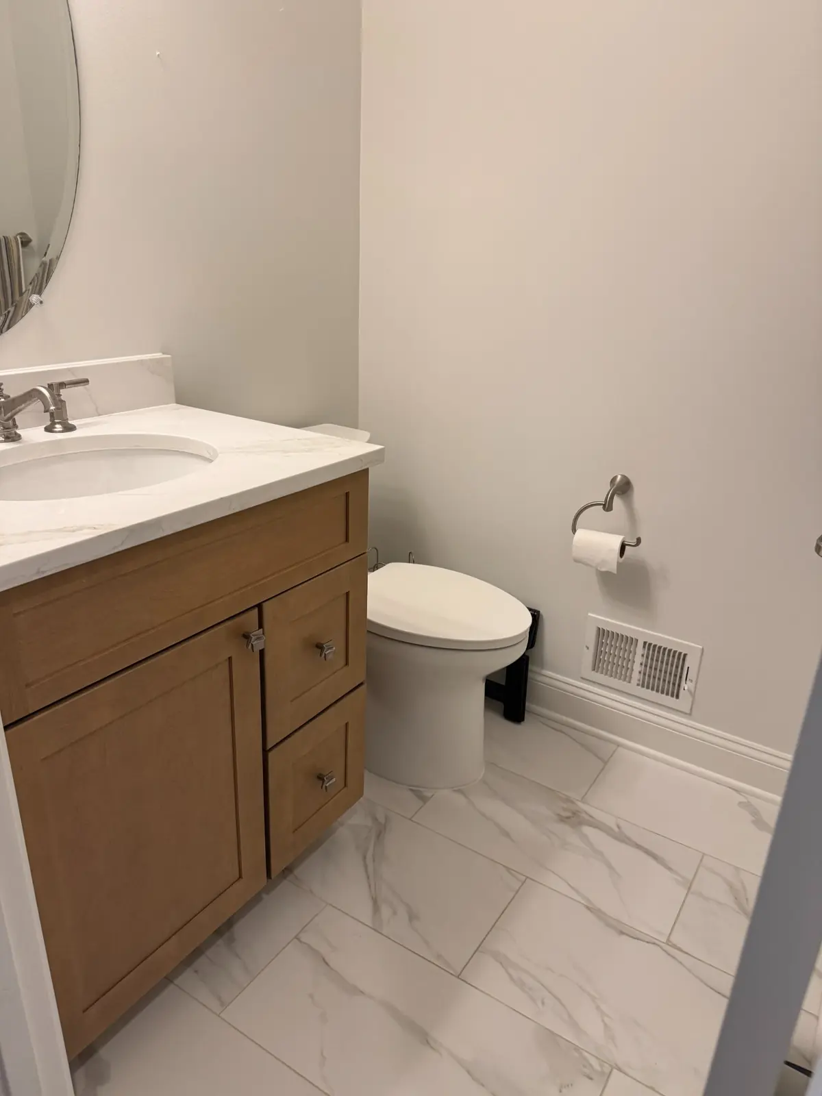 Half bath with a light wood vanity, marble-look quartz top and a marble-look tile floor