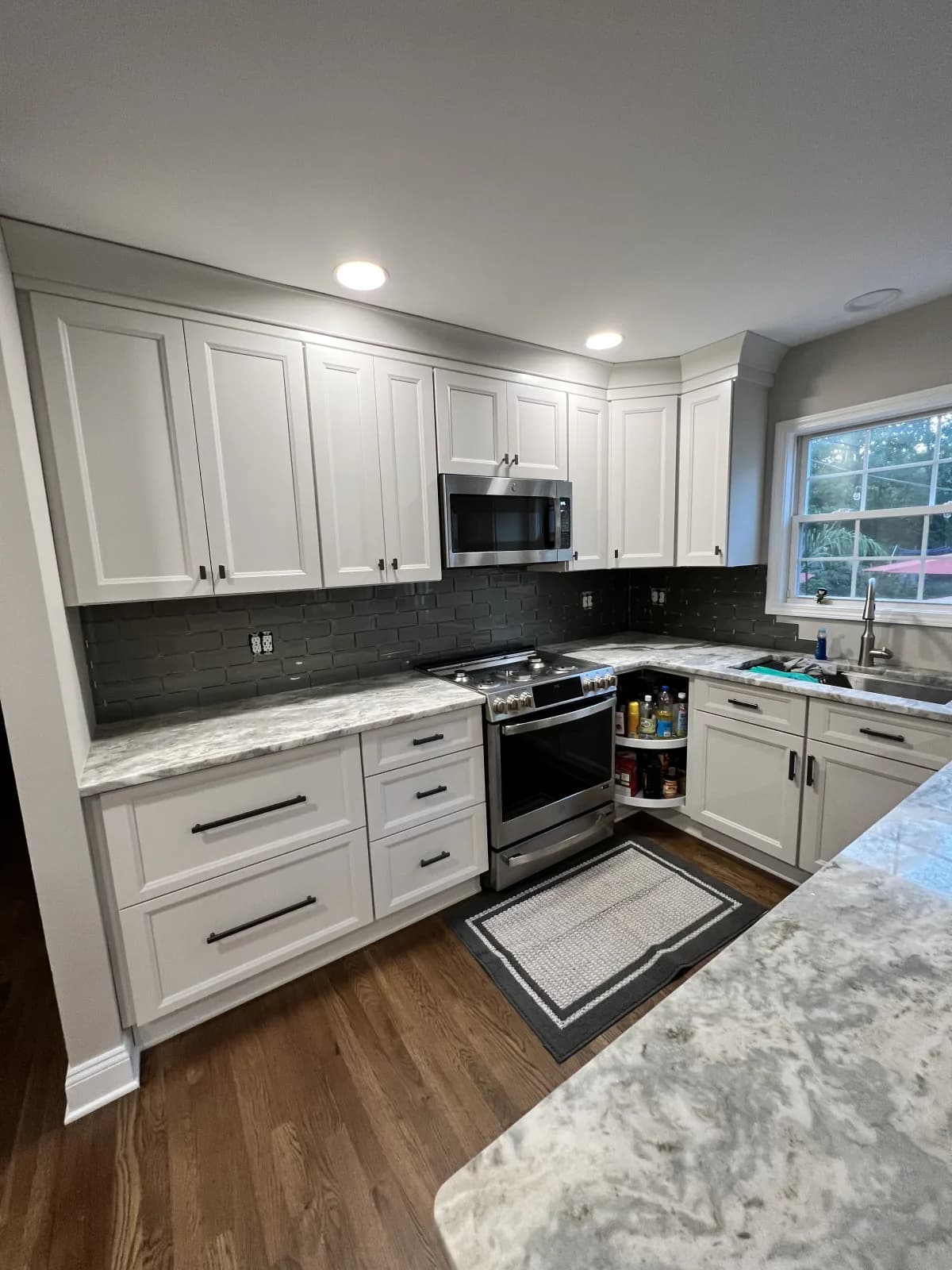 White shaker kitchen with a grey tile backsplash behind a range