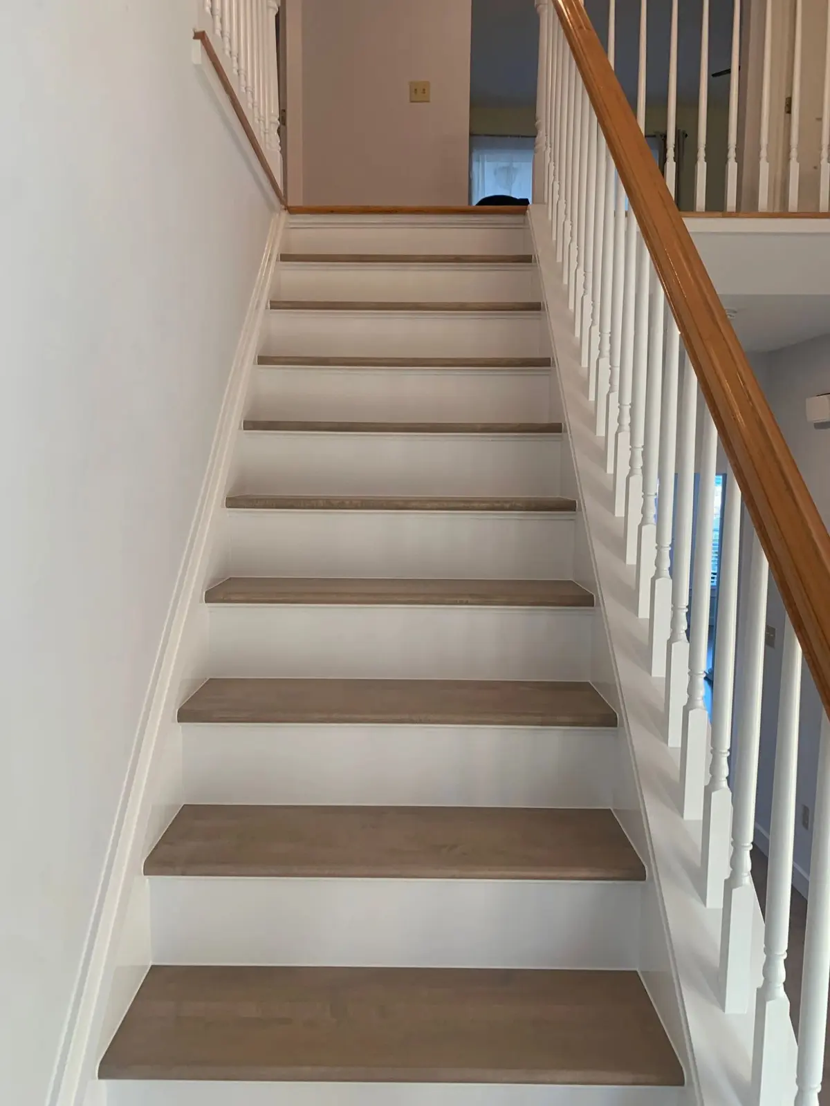 Painted white staircase with refinished light oak treads and a wooden handrail