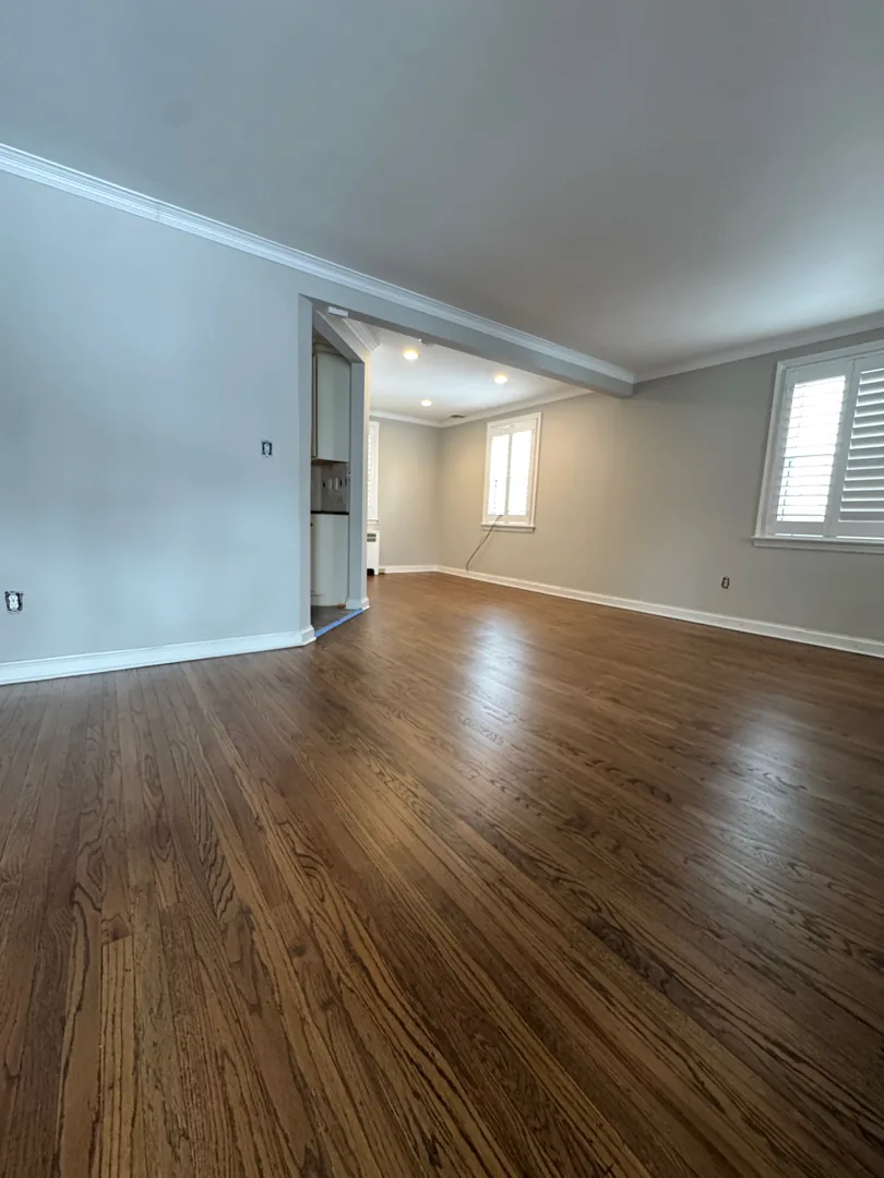 Living room with a dark refinished oak floor and an open doorway to the next room