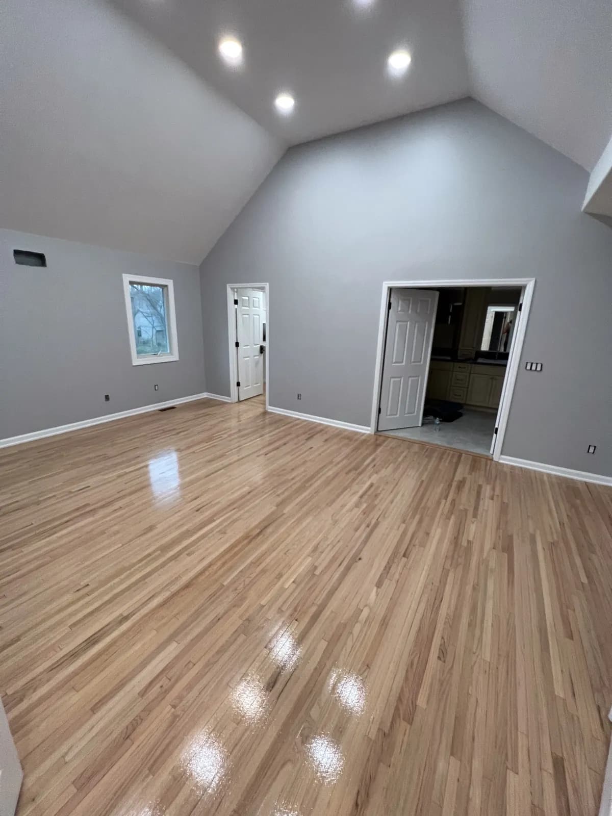 Light oak floor in a room with a vaulted ceiling and recessed lighting