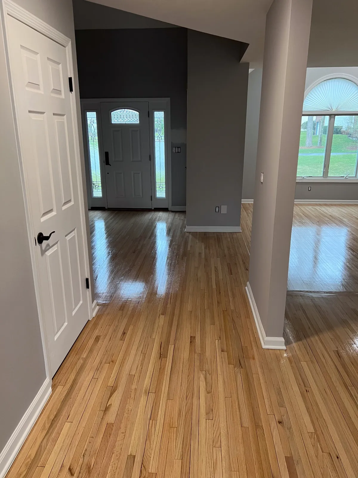 Golden oak hallway leading to a front door with sidelight windows