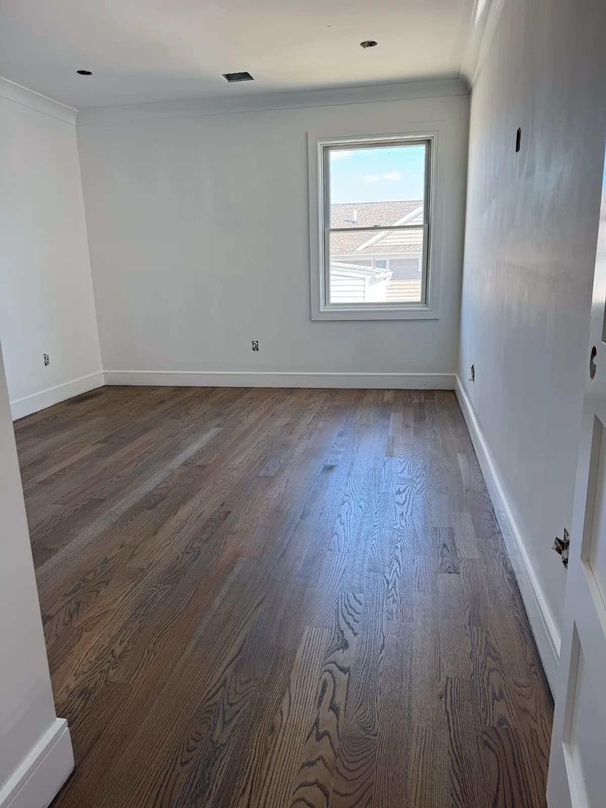 Bedroom with a dark refinished oak floor and a single window