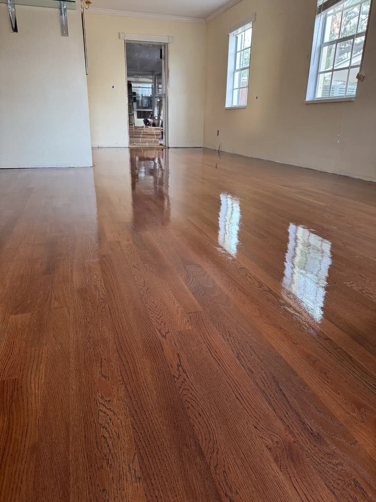 Refinished red oak floors with a high-gloss finish running the length of a room