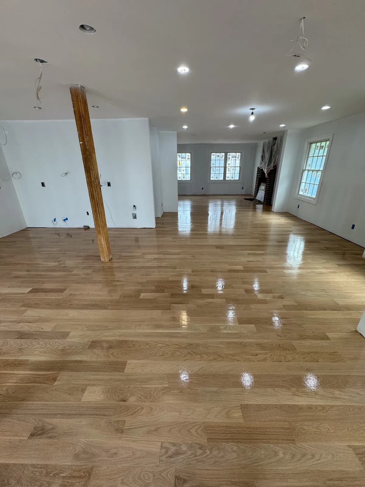 Light oak floor in an open room still under renovation, with an exposed support post