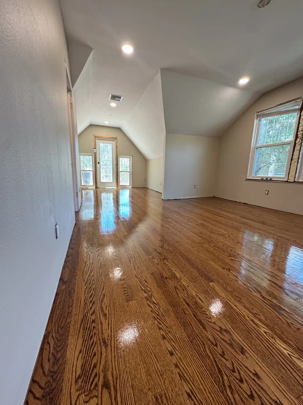Golden oak hallway under a vaulted ceiling with an arched window at the end