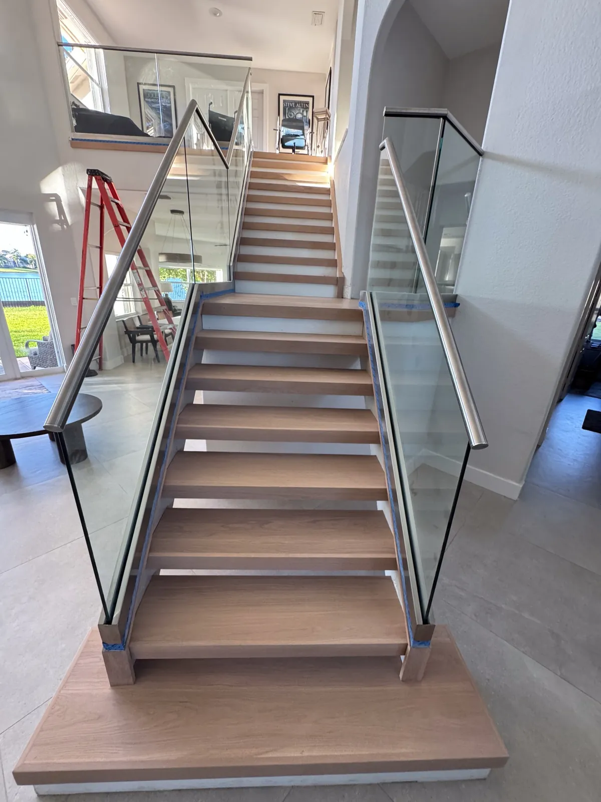Open staircase with new wood treads and a full-height glass railing