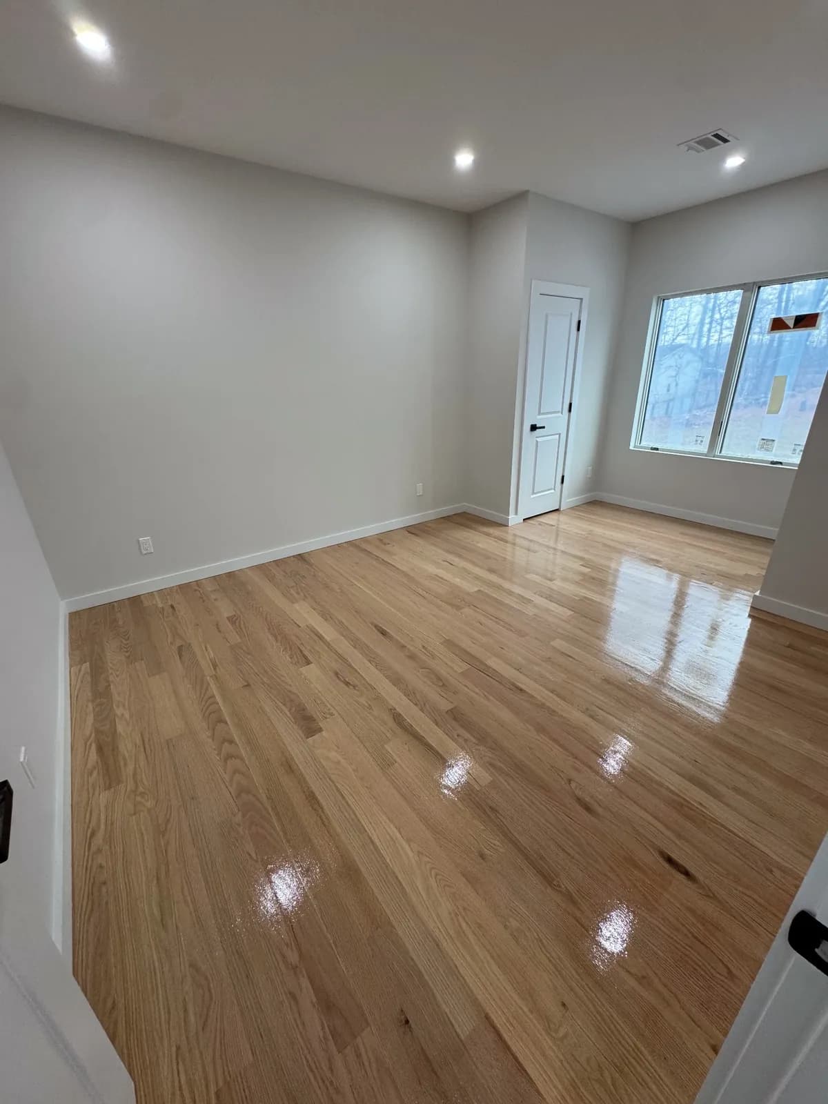 Light oak floor in a bright room with white walls and a single window