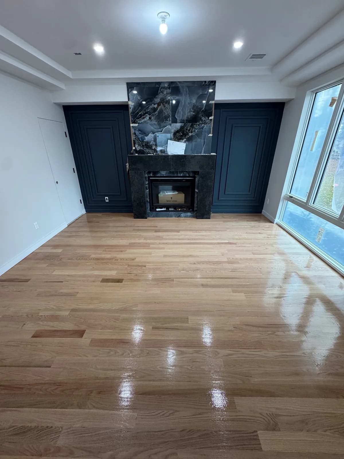 Living room with a navy fireplace surround and freshly refinished hardwood floors