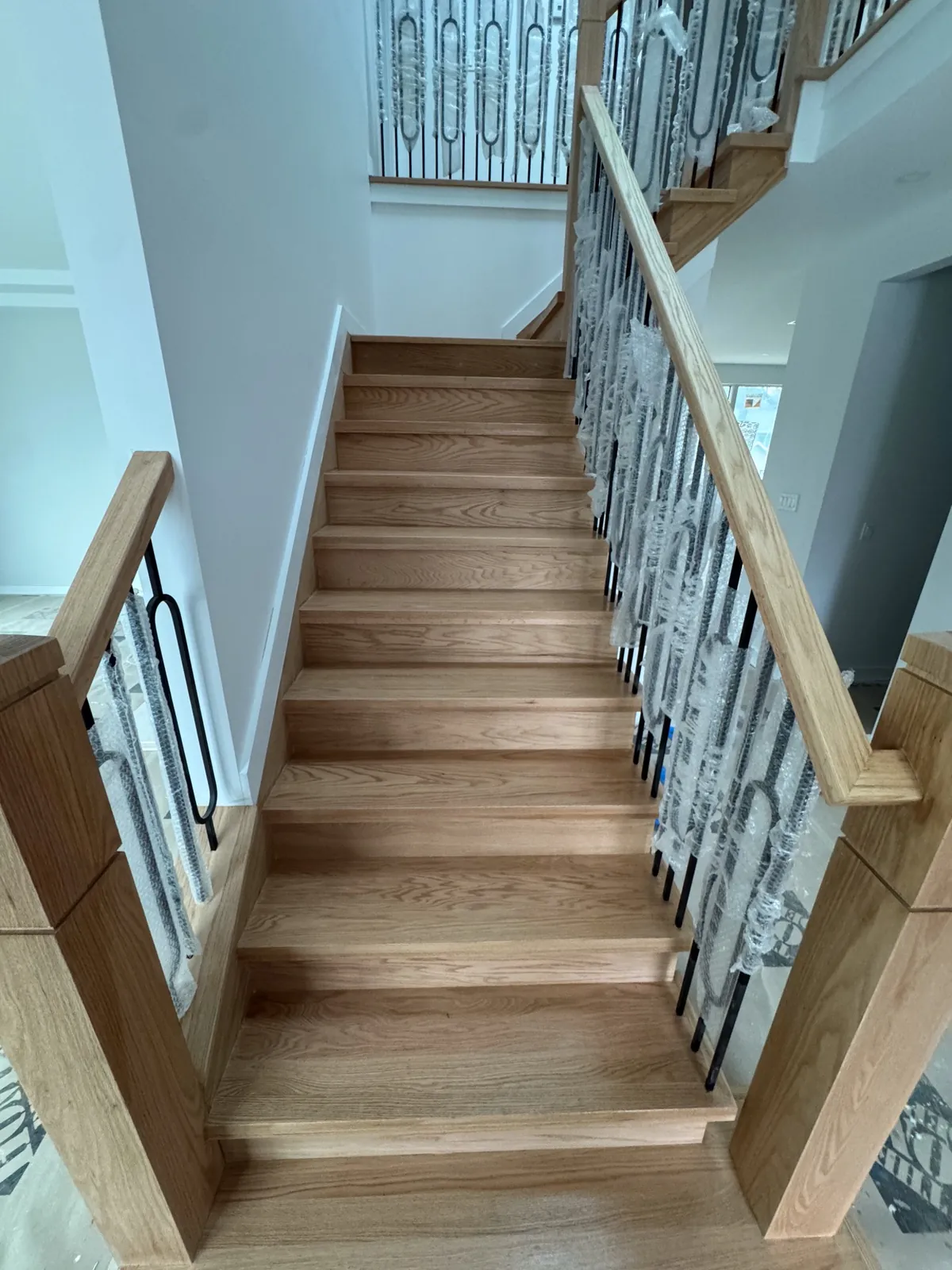 Oak staircase with wrought-iron balusters rising between two railings