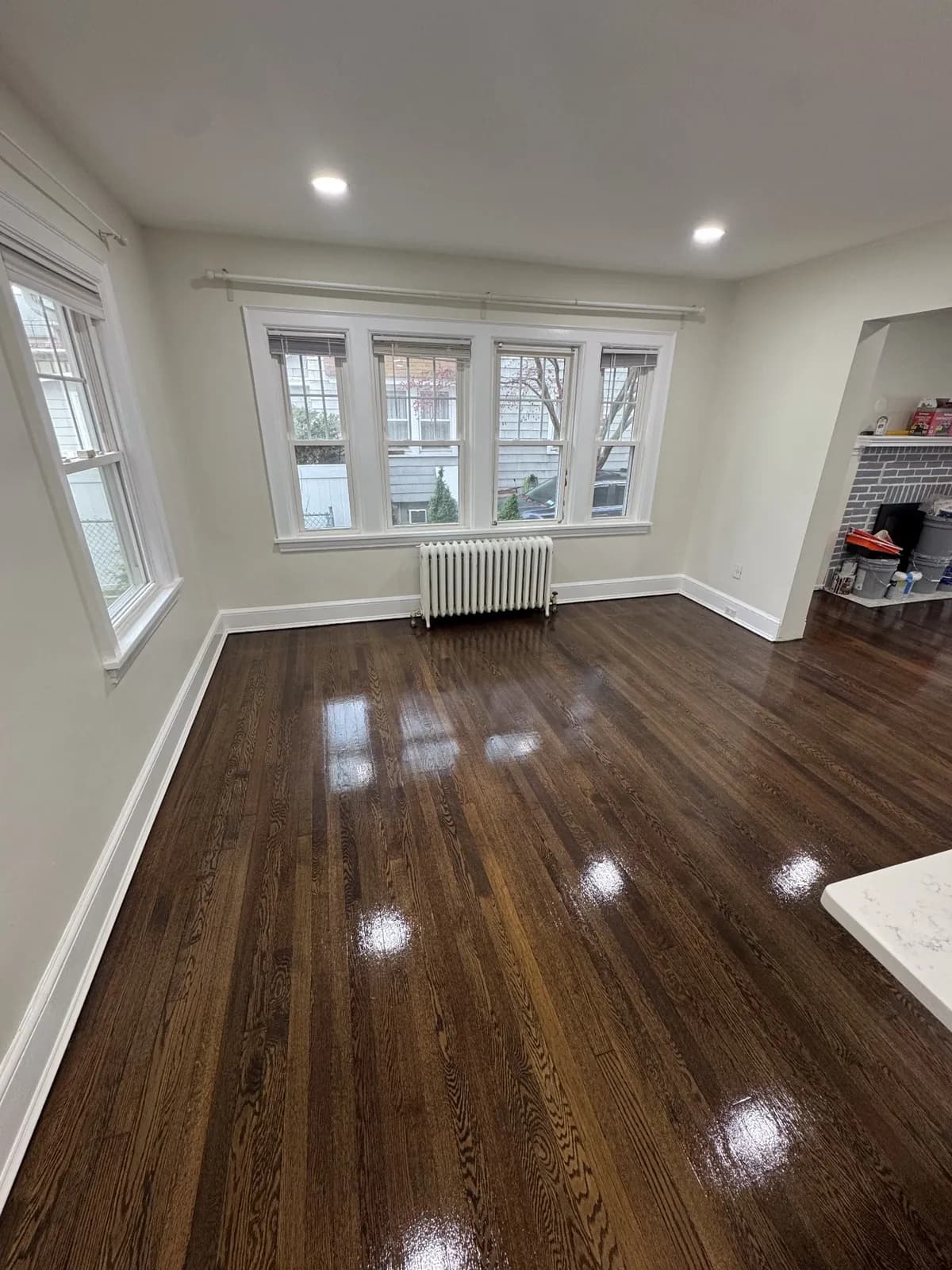 Dark-stained oak floor in a room with a radiator under a bank of windows