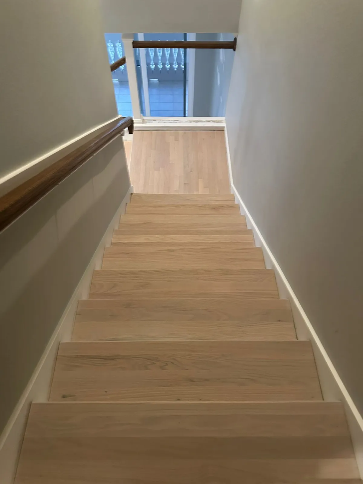 Pale oak staircase seen from above, descending toward a window