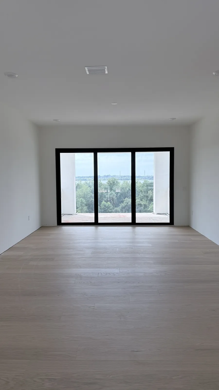 Pale oak floor in an empty open-plan room with black-framed sliding doors