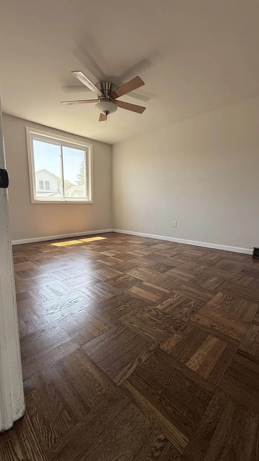 Dark-stained parquet floor laid in a basket-weave pattern beneath a ceiling fan