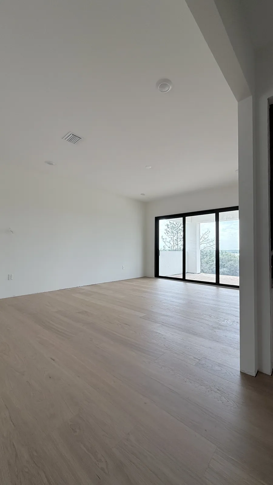 Pale oak floor running through an open-plan room toward a glazed door