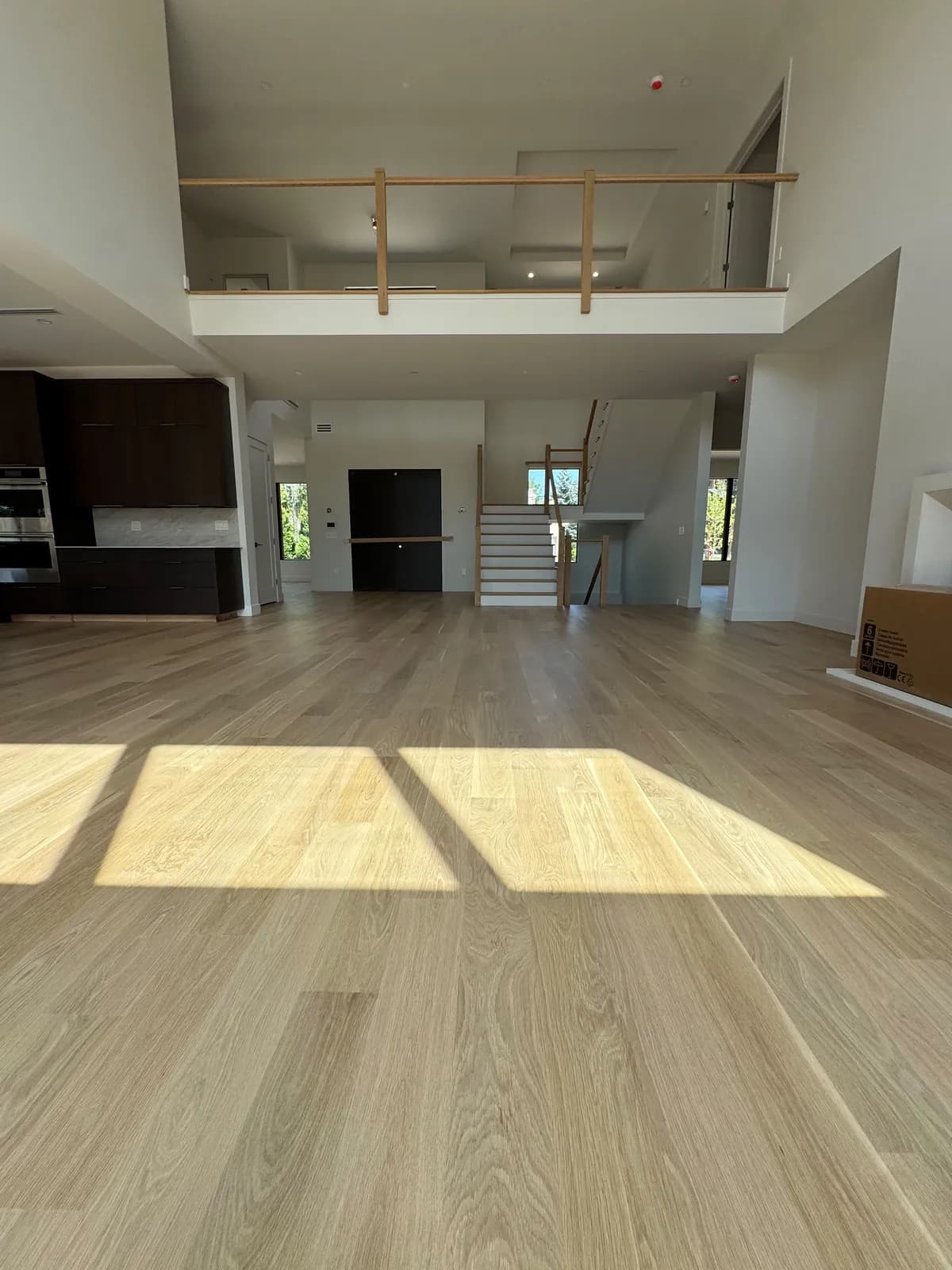 Pale oak floor in a double-height room with a mezzanine railing above