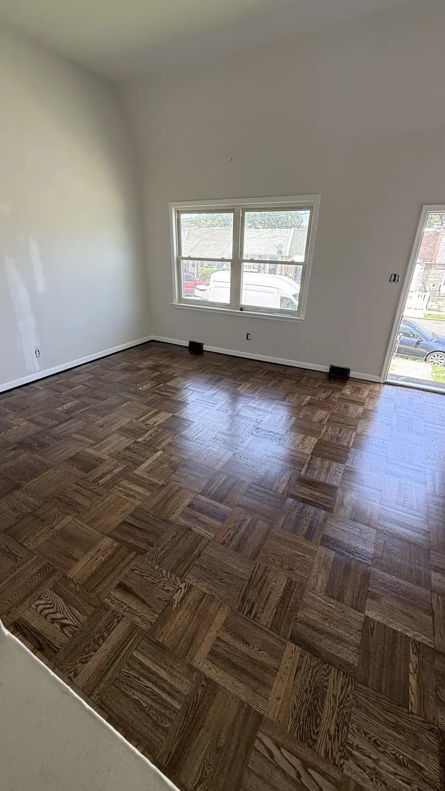 Dark parquet floor beside a window and a sliding glass door