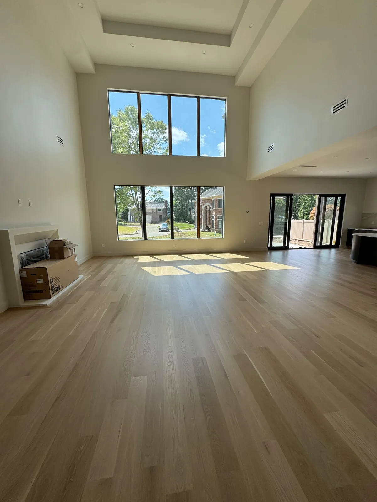 Pale oak floor in a double-height room with tall windows on two levels