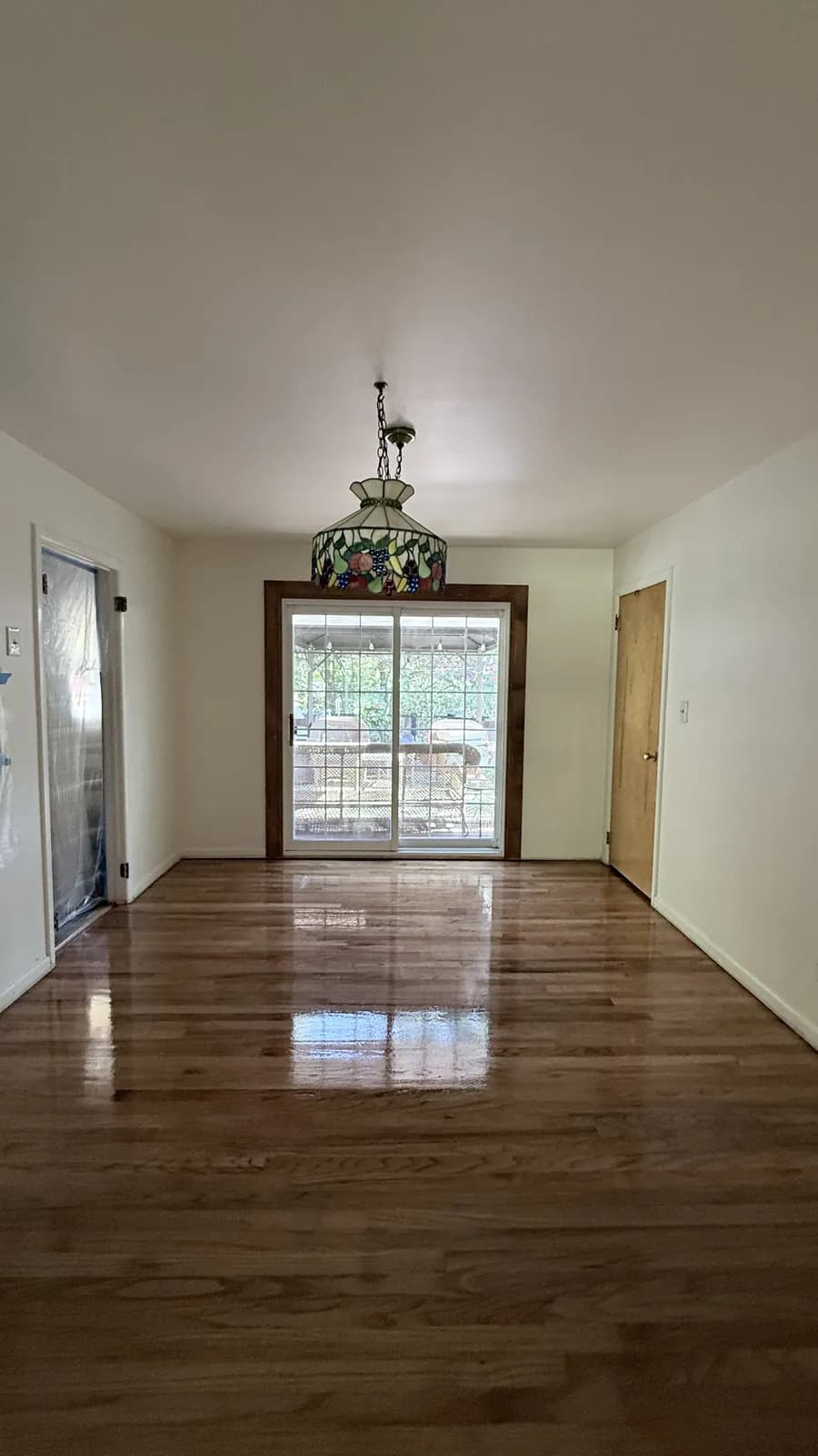 Medium-toned oak floor in a dining area under a stained-glass chandelier