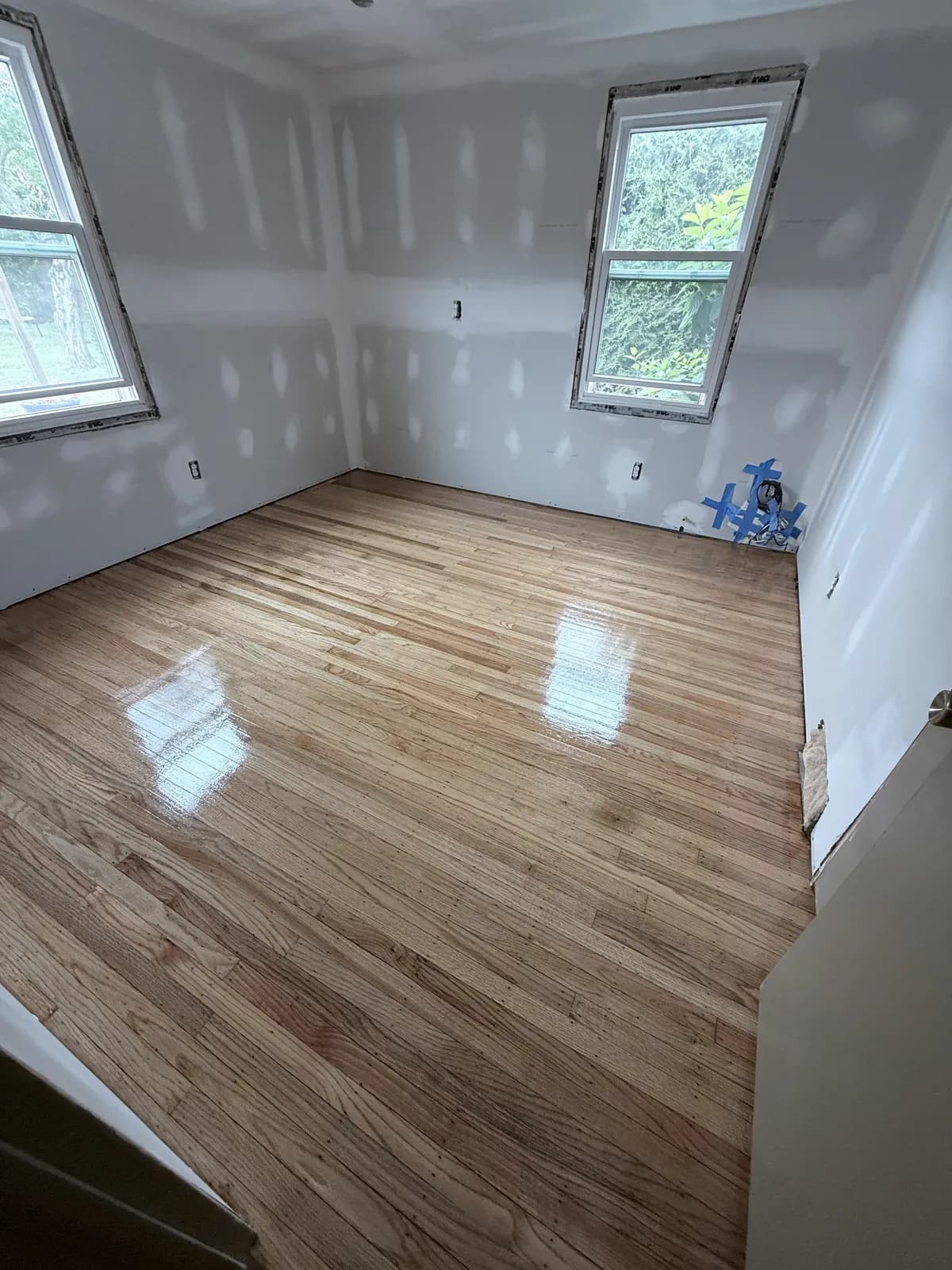 Freshly finished honey oak floor in a room still being renovated, walls not yet painted