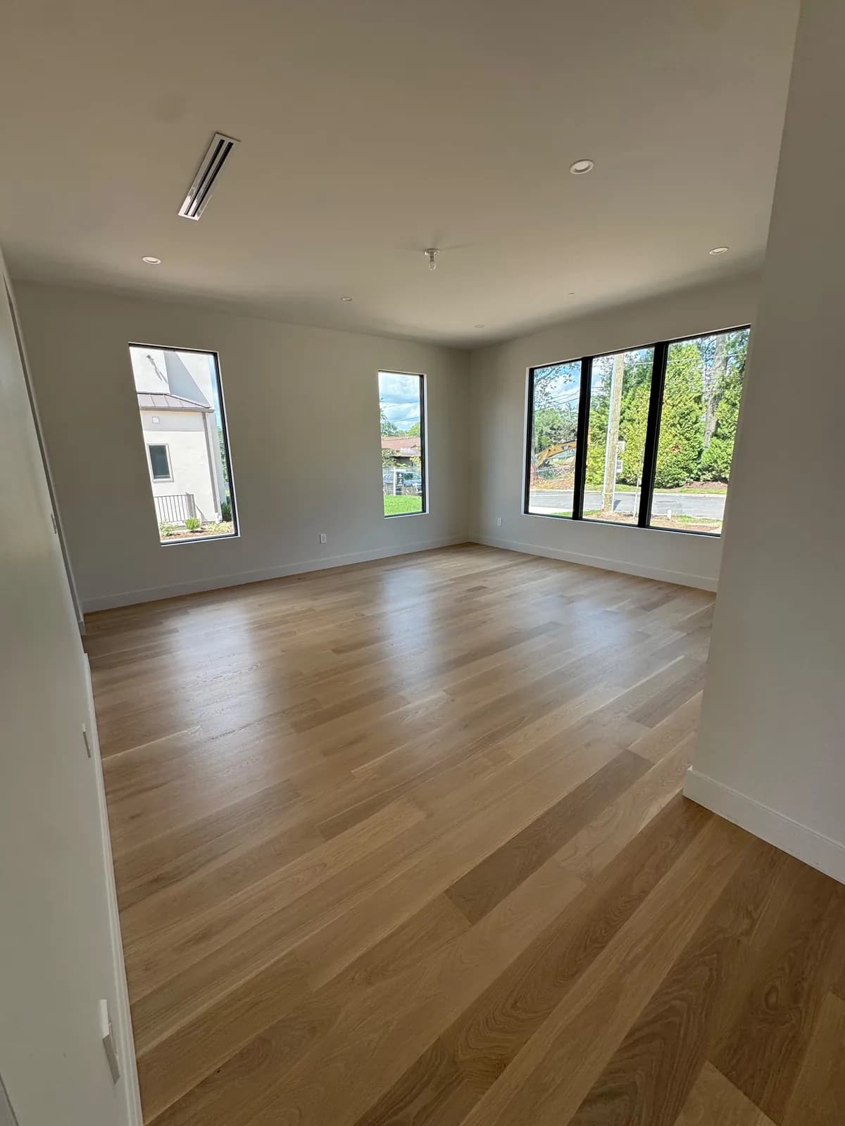 Pale oak floor in a room with two windows looking onto trees