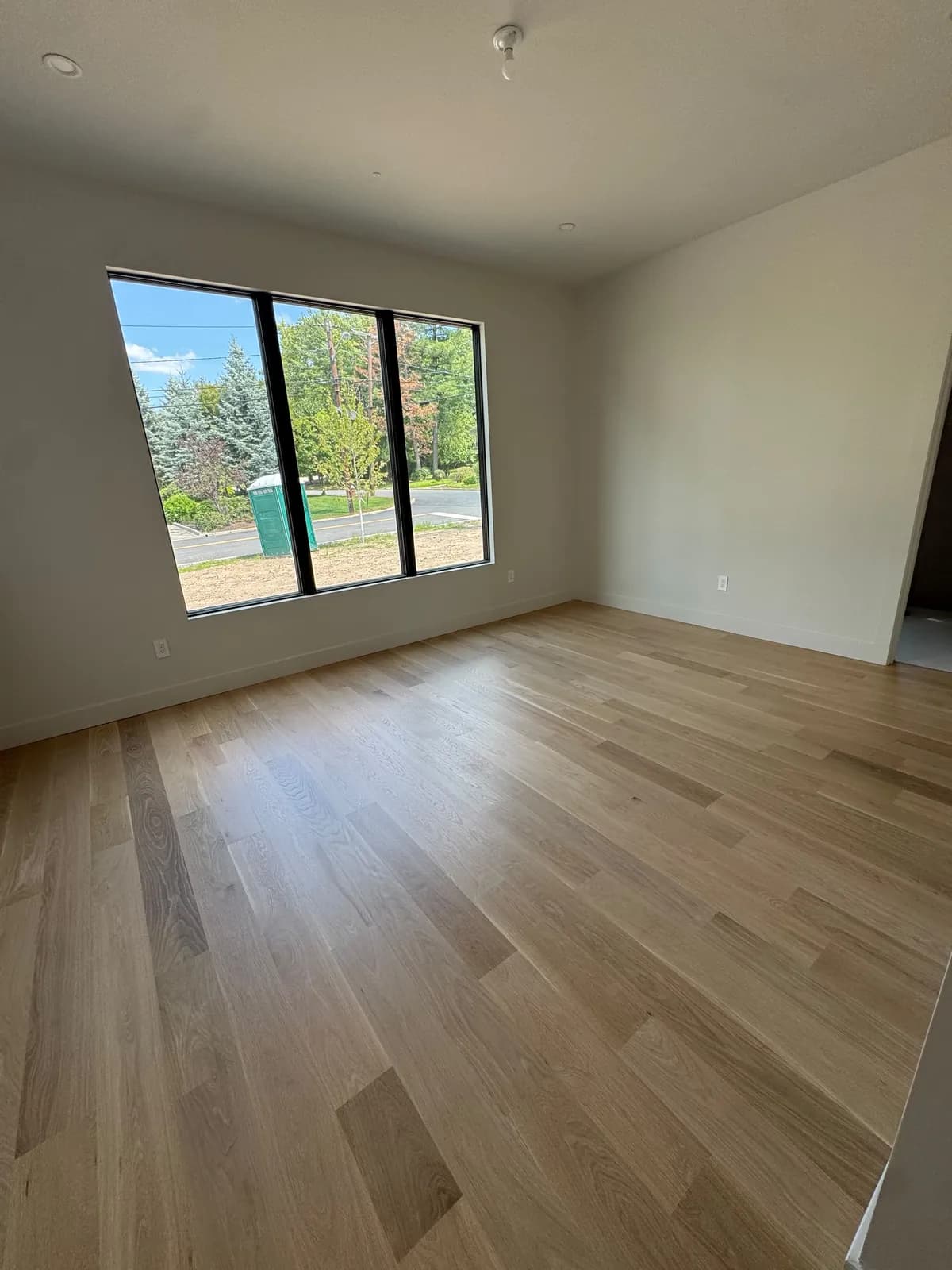 Pale oak floor beneath a large picture window
