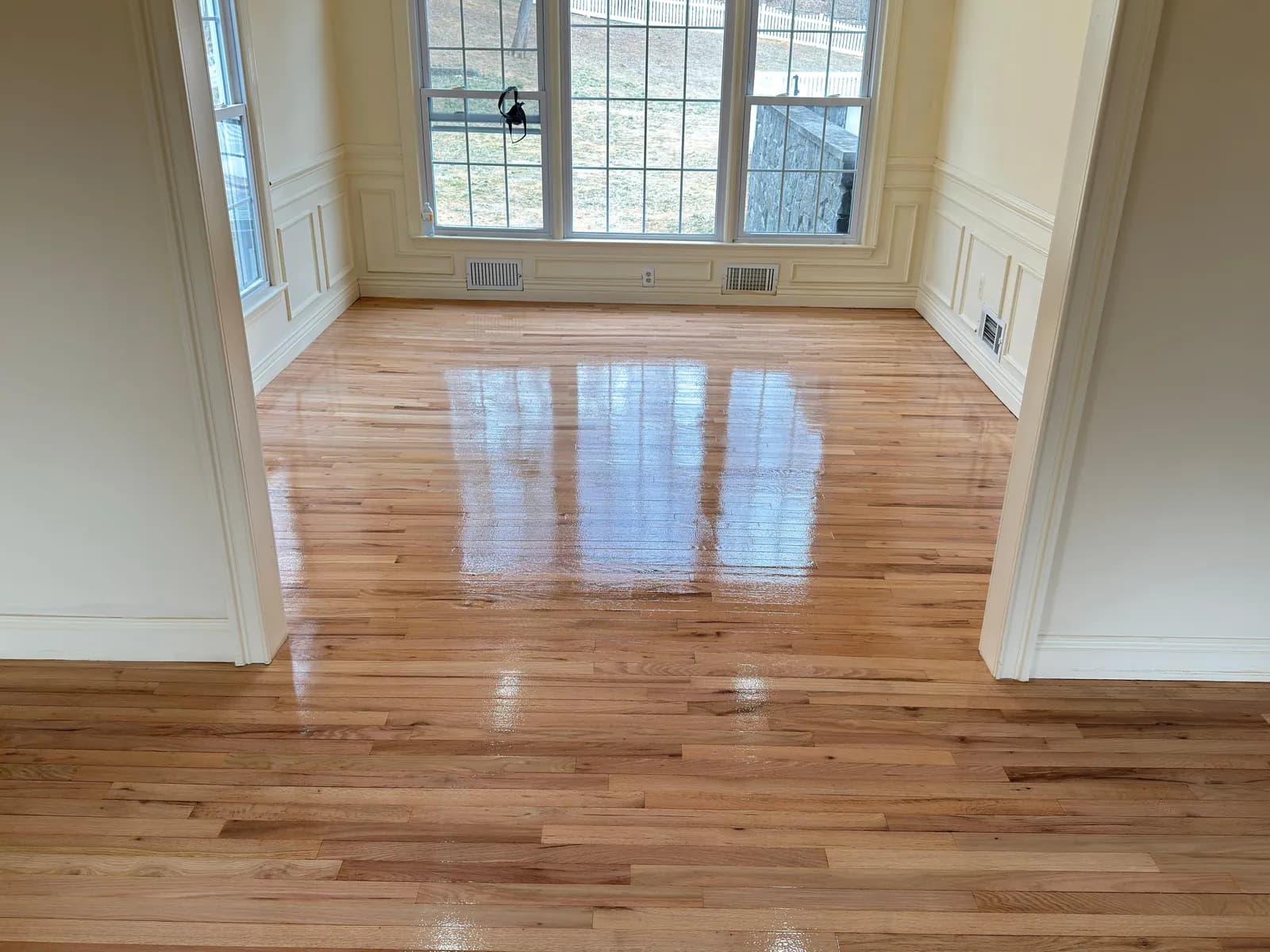 Honey oak floor in a paneled room with a bank of windows on the far wall
