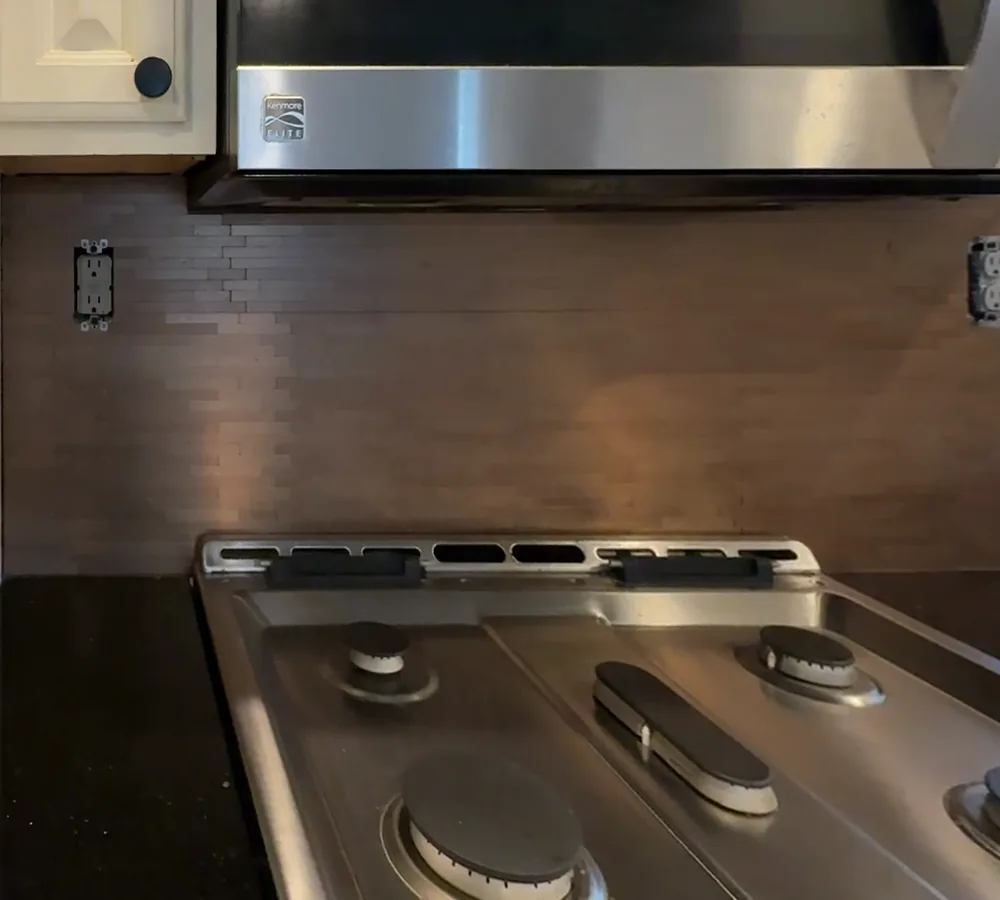 Before: a dark brown linear tile backsplash behind a gas range, under a microwave