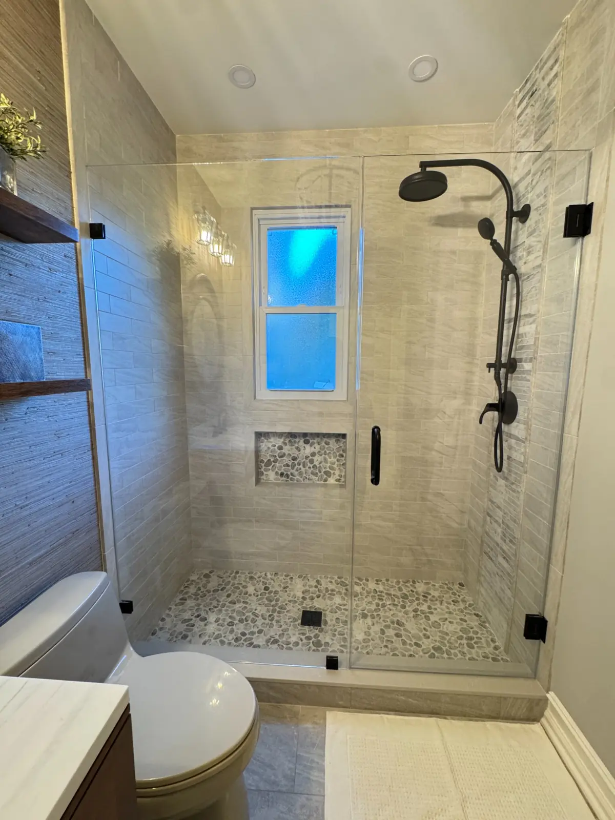 Remodelled bathroom with a glass-enclosed tile shower and dark fixtures