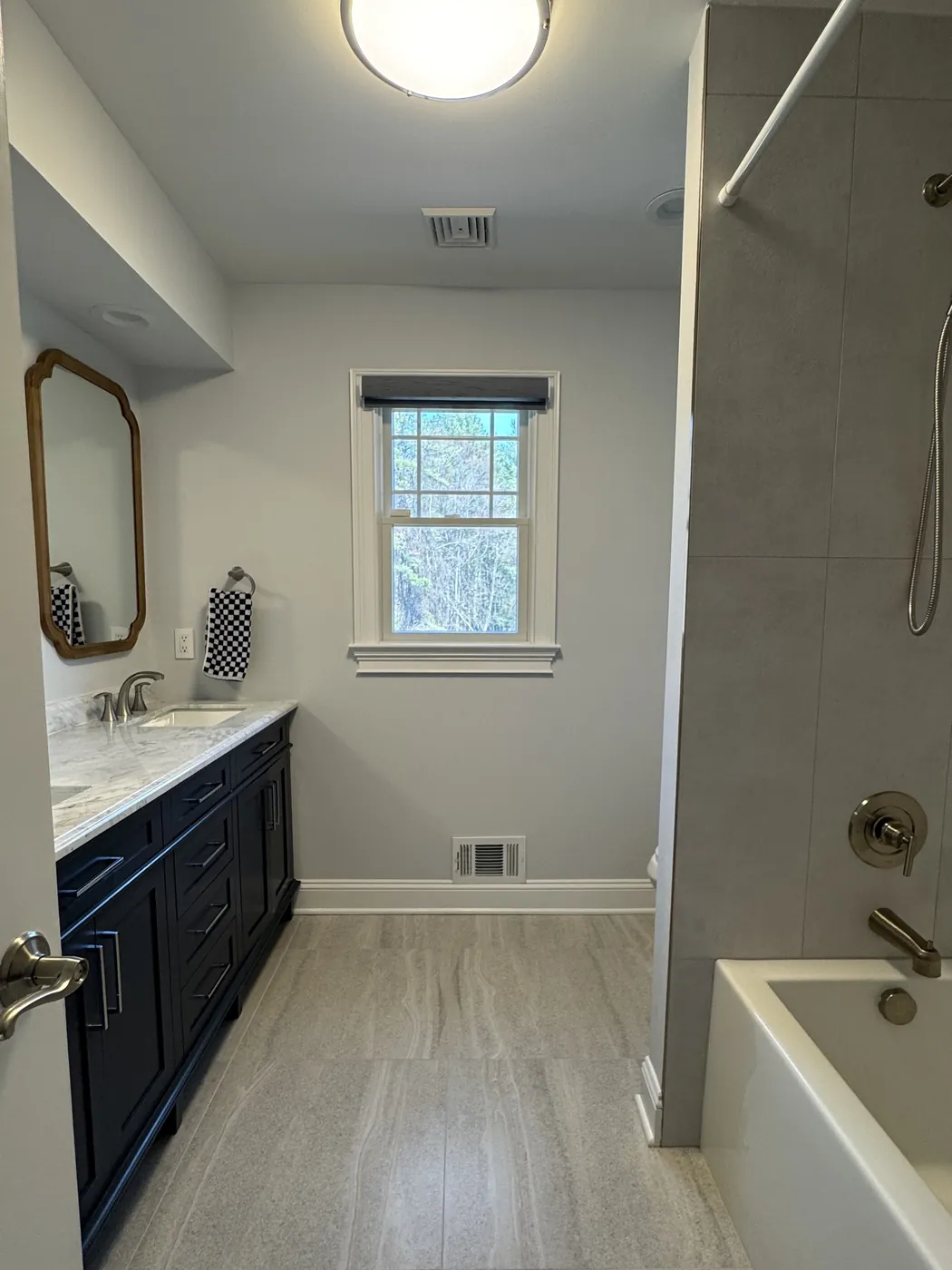 After, seen from the same doorway: the tub walls tiled in large-format gray porcelain and a new porcelain floor, by Summit Home Services