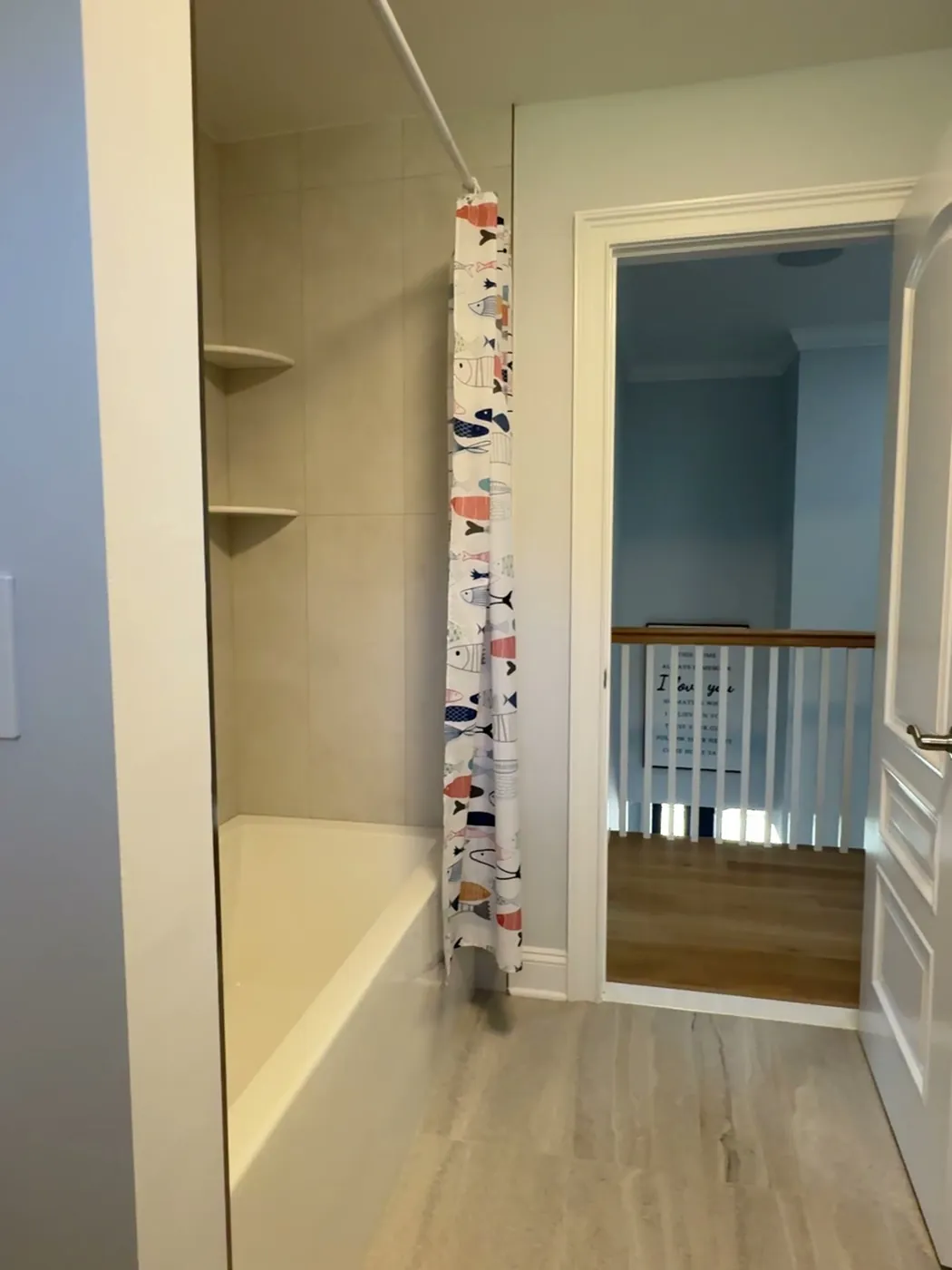 After: the same tub retiled in large-format gray porcelain with corner shelves and a matching floor, by Summit Home Services